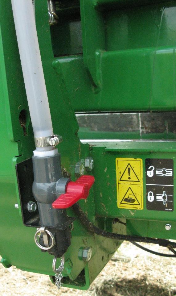 Locate the drain/fill line on the right side of the baler. Open the cam-couplers (A) and remove the protective plug (B).