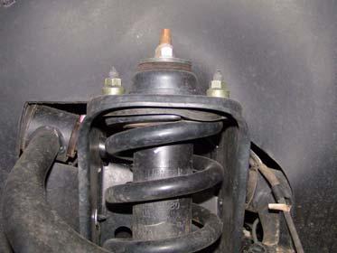 Remove three nuts at top of strut securing it to vehicle frame.