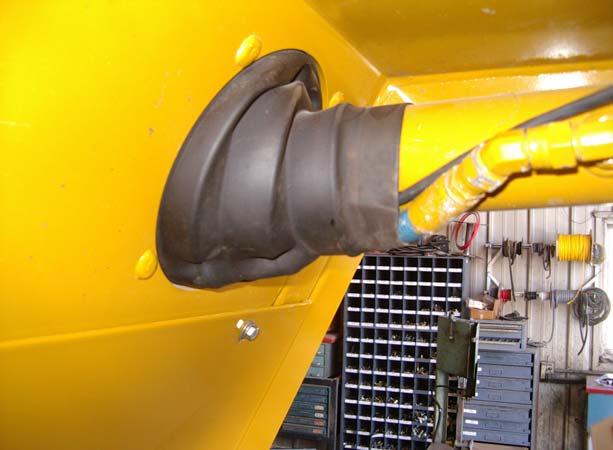 Route the cable through the left steering cylinder rubber boot next to the