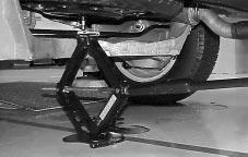 4. Lower the jack by turning the folding wrench counterclockwise. Keep lowering the jack until the compact spare tire is resting on the folding wrench. 1.