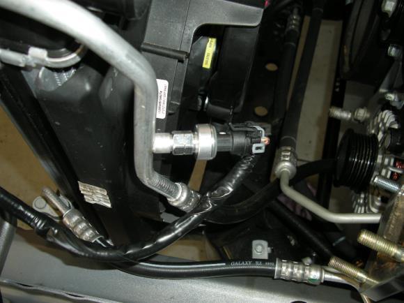 11. Disconnect the AC pressure sensor harness. Remove the sensor and O-ring. The shrader valve inside the AC line will prevent refrigerant from escaping. Install the supplied cap over the port. 12.