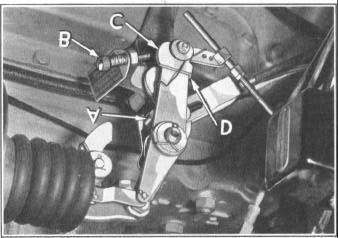 With the transmission in low gear, hold cam (C) against stop screw (B) by pressing forward at point (D).