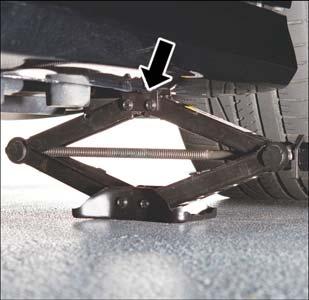 4. Place the jack underneath the lift area that is closest to the flat tire. Turn the jack screw clockwise to firmly engage the jack saddle with the lift area of the sill flange.