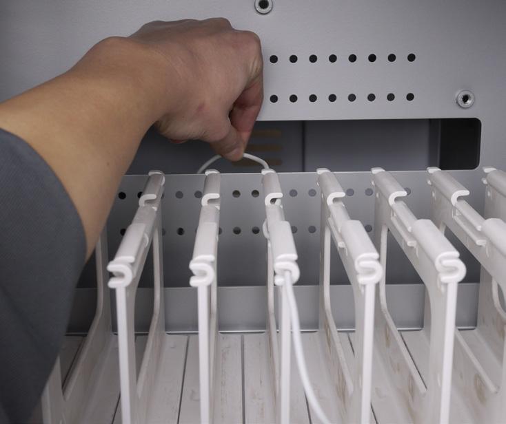 In the IT area, poke cable clips into the holes in the pegboard divider and route cords. Plug in each power adapter, then connect each cord to an adapter.
