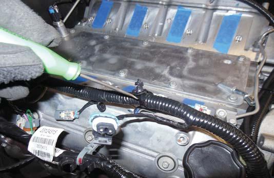 100. Use a pry tool hook to remove the injector harness mounting