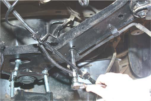Remove the e-brake and brake line cable from the upper control arm using a 10mm socket to allow the control arm spacer to