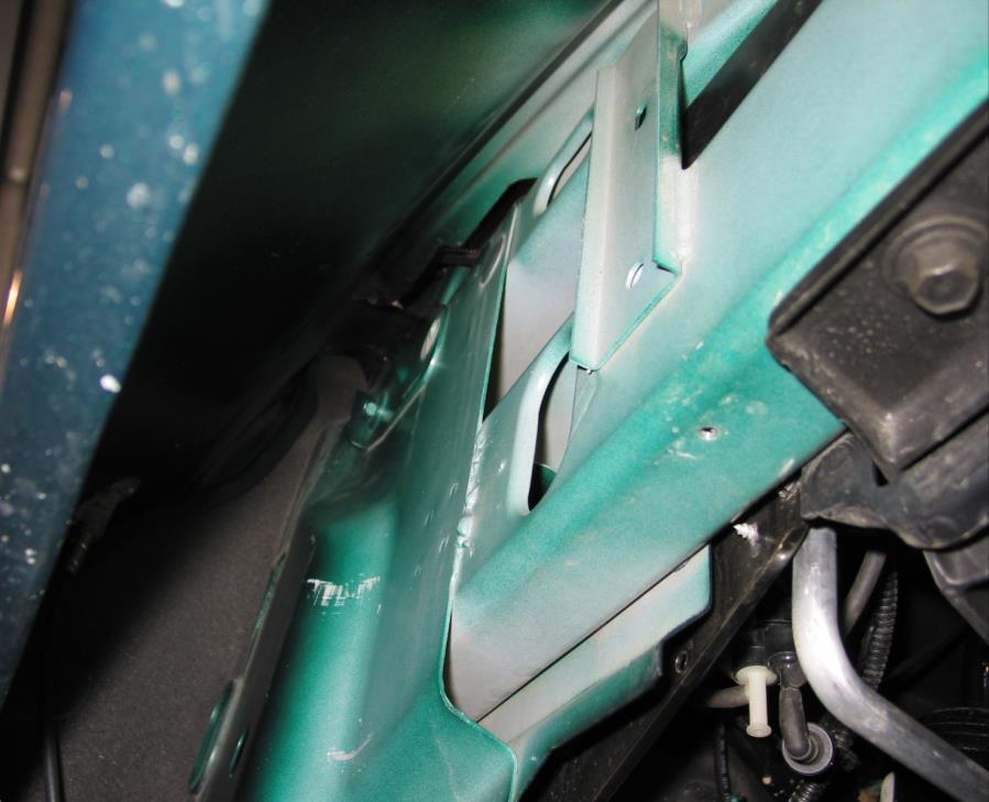 Locate the hood support bolt up inside the fender well; it is very close to the bottom of the radio antenna.
