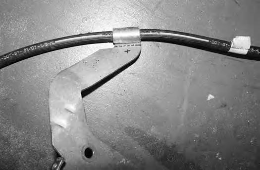 The brake line axle bracket will need to be trimmed. Cut the brake near the rolled end holding the OE brake line (Fig 3).