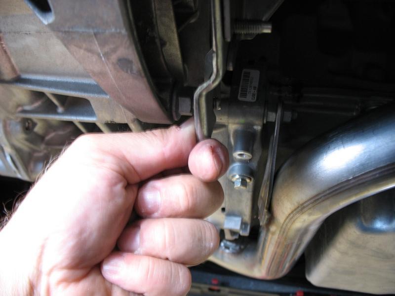 3. Once the belly pan is removed and the rear mount is exposed, remove the 6 nuts shown below that secure the down pipe support bracket to the transmission with a 13mm 6-point socket and 6 extension.