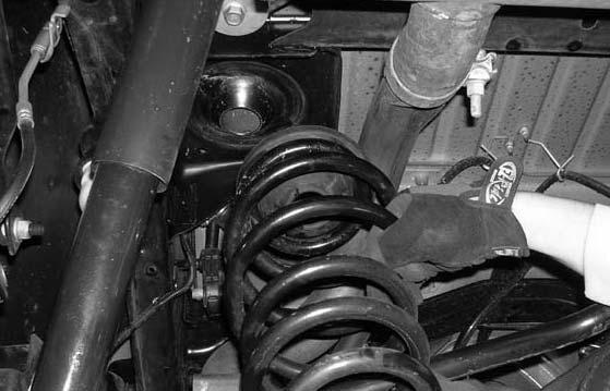 Carefully lower down on both hydraulic floor jacks until the rear coil springs can be removed.