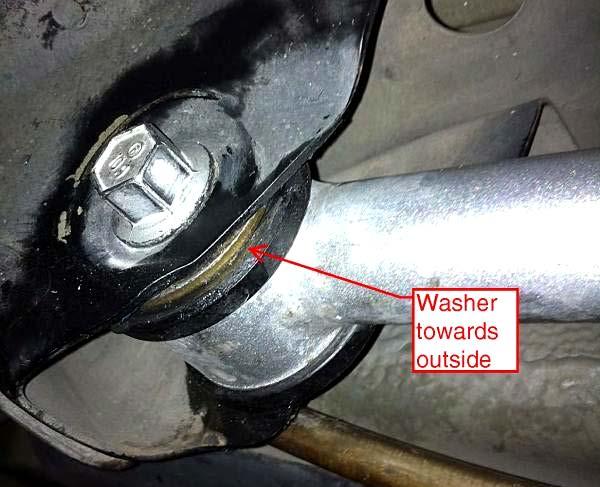 Install (1) of the provided washers on the control arm, placing it to the outside of the