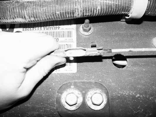 Figure 12 17. Remove the front half of the parking brake cable from the body mount. Compress the retaining tabs with pliers and push the cable through the hole Figure 13. 18.