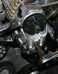 Using a ½ drive breaker bar, rotate the tensioner clockwise just until it is possible to slide the tensioner locking pin through one of the holes in