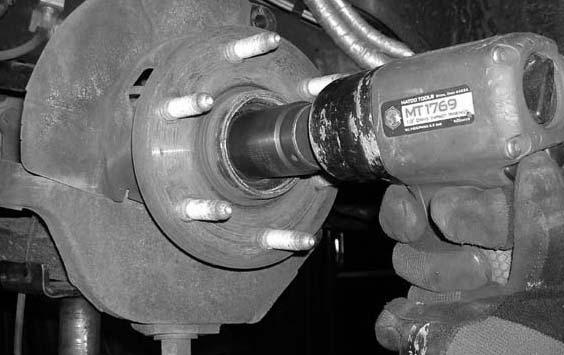 Working on the driver side, loosen but do not remove the nut that connects the upper control arm ball joint to the