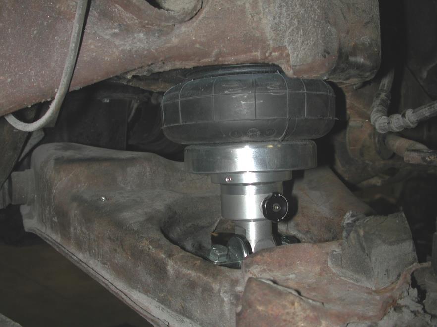 Note that the Shockwave trunnion sits on top of the arm as opposed to the factory shock, which bolts to the bottom side of the car. You will have to remove the two nuts. 14.