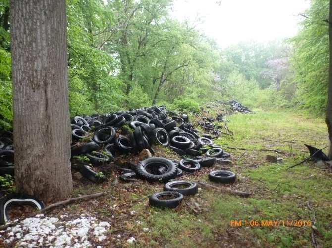 Some scrap tires are mixed with scrap metal, soil, and other solid wastes in a berm that roughly follows the property perimeter.