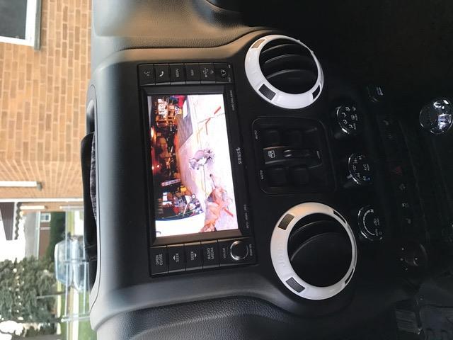 Activate the forced reverse camera by holding the Preset button (center button on the back left of the steering wheel) with the jeep in