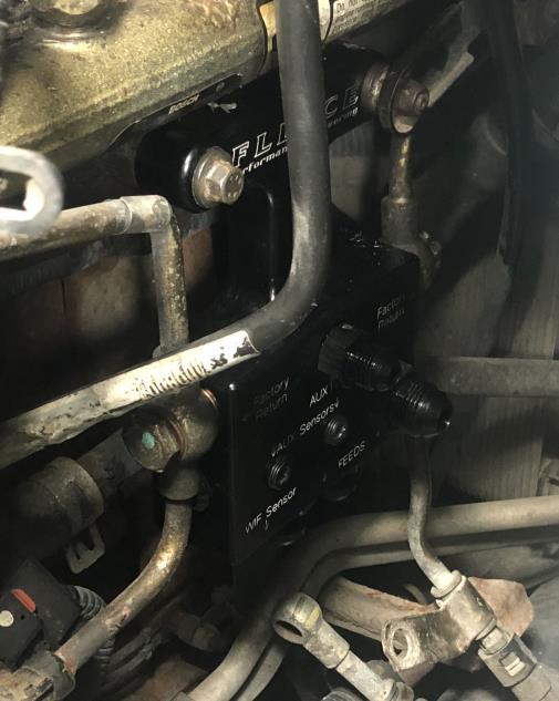 Remove the two return line connections and the feed connection. Unplug your WIF sensor and remove the two (2) - 10mm mounting bolts that attach the OE fuel filter housing to the cylinder head.