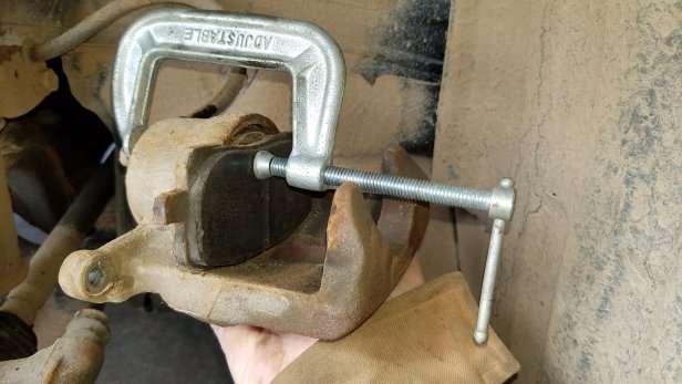 Find a large C-clamp, and put it over the break caliper has shown.