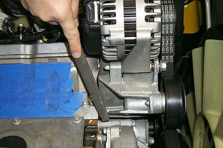 Using a fi le or die grinder, remove material from the alternator mounting bracket marked in
