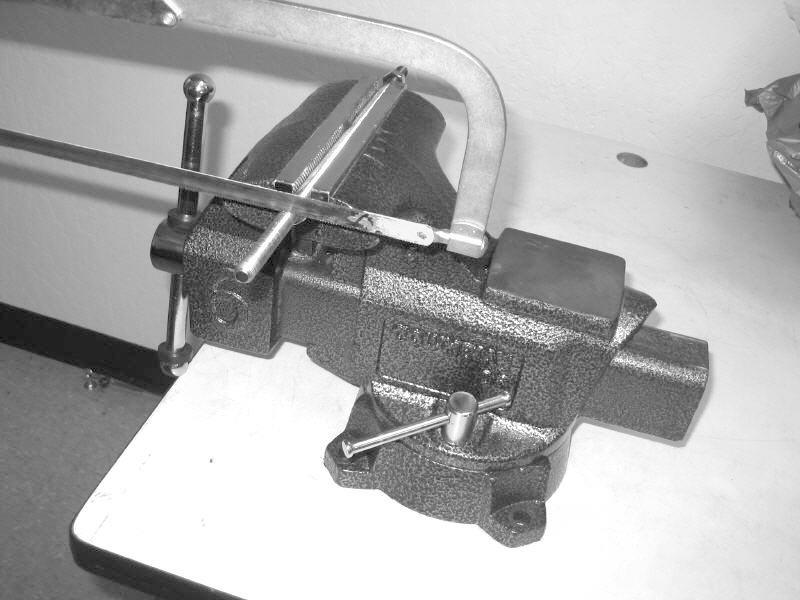 Use a hack saw to cut the linkage rod to length while it is held in a bench vise. Note: Secure the rods in a vice or other device while cutting. Protect the threads so they are not damaged.