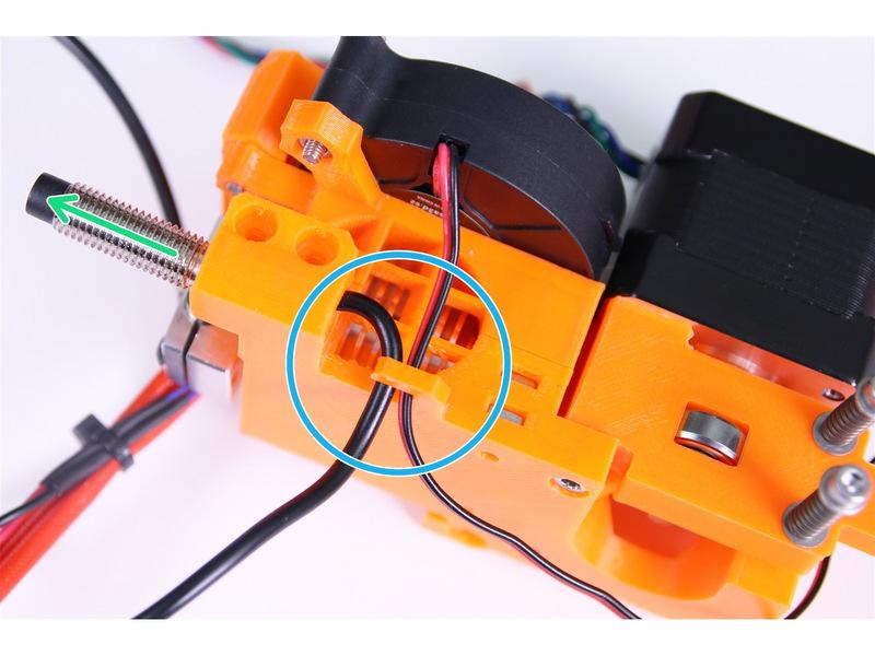 Guide both cables through a cable clip on the extruder body as shown in the picture.