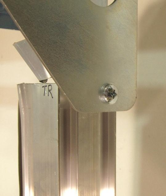 As required, guide the bottom of the vinyl door into the extrusion and align the aluminum standoff with the right bracket.