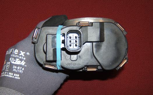 Hold the throttle body with your hand, so that the throttle position (TP) sensor cover is facing upward as
