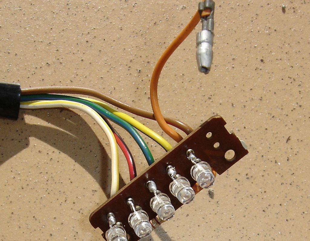 Position the LED legs against the first two pins with the flat side pin (cathode) towards the White/Yellow wire and the round side