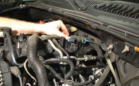 Disconnect the engine knock sensor connector and steel-mounting clip from the intake manifold by prying it