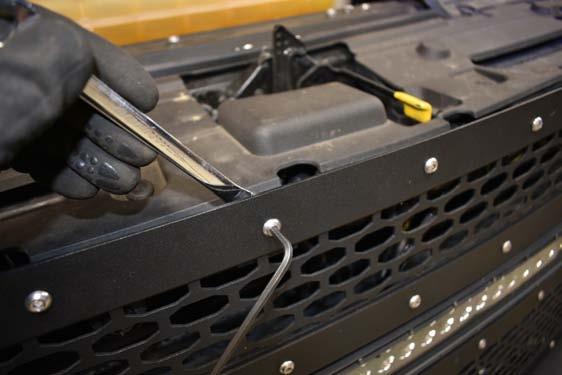Remove the 5 upper bolts on the mesh grille and position the new bracket into position. See Photo 7. 8.