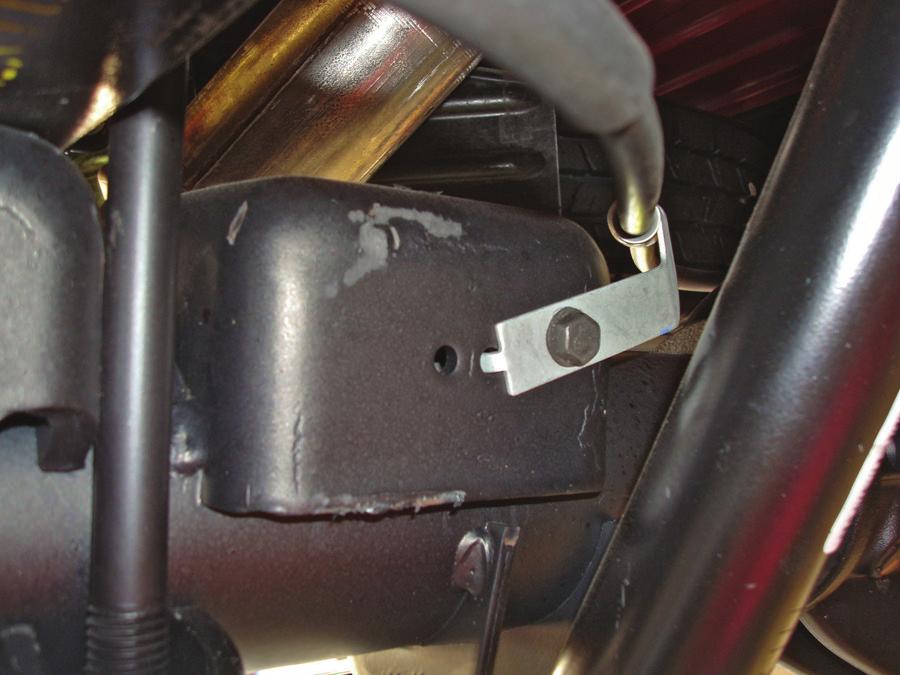 4. Remove the three bolts that hold the brake line and emergency brake cable brackets to the jounce bumper strike plates, forward and behind the rear axle (Figs. 6 & 7). 5.