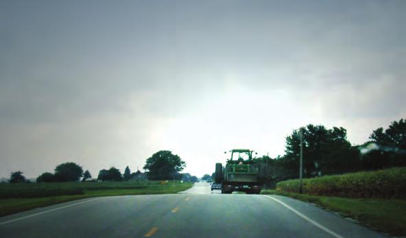 9 This plated trailer hauling a tractor between farms is displaying a slow moving vehicle sign.