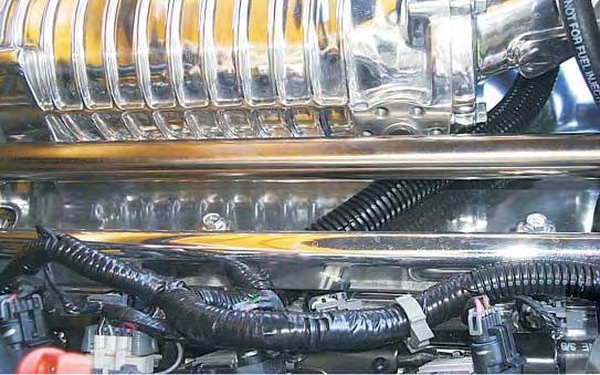 185. With the wiring harness routed under the inlet manifold, mount the throttle body using the original nuts and