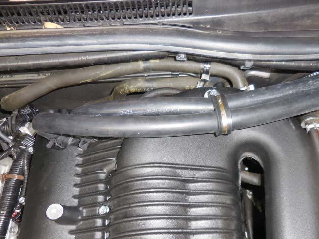 Run the hose along the earlier hose in front of the brake fluid reservoir, trim the remaining end as necessary, and install it on the inlet barb of the intercooler reservoir with the screw clamp.