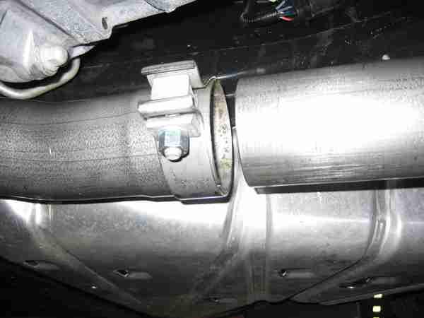 Place TORCA clamp on inlet side of driver side muffler in the correct orientation and with the bolt to the outside