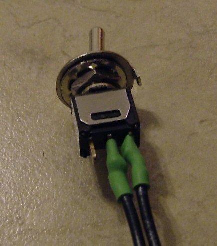 A wire twisted around a switch lead Slide the heat shrink over the soldered switch pin and shrink, covering up all exposed wire as illustrated below Figure 32.