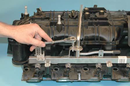 For earlier model years, remove the two E6 (inverted Torx) bolts (one on each side) of the crossover tube retaining brackets for the fuel rails. 60.