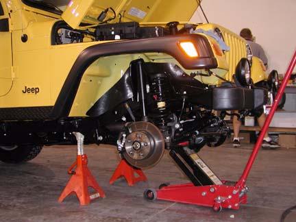 Using a hydraulic jack, slowly lift front axle until front tires are 3-5 off ground.