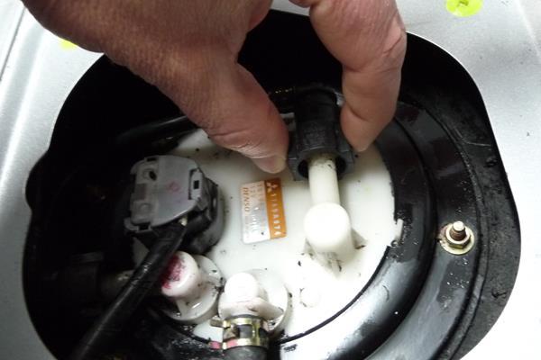 16. Remove the high pressure line from the fuel pump hanger fitting by first squeezing the 2 opposing tabs and then pulling away from the fuel pump hanger