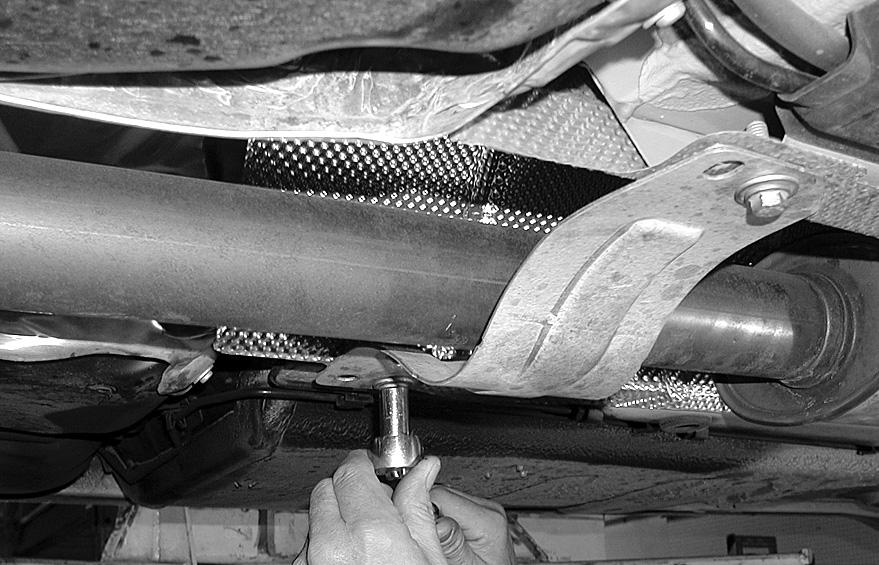 Remove the plastic cover over the rear of the shock absorber by rotating the plastic cover 1/ turn. The plastic cover is labeled open/close on its top.