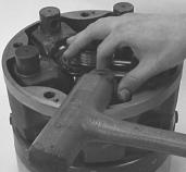 By hooking a finger under the piston lift up the piston, tapping the cylinder trunnion with a rubber hammer to loosen the piston from the shaft.
