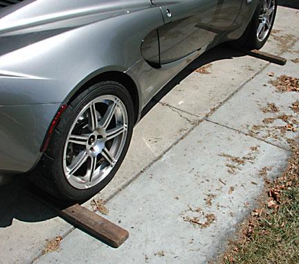 Block both the front and rear wheels on the opposite side of the car that you are going to jack up first.