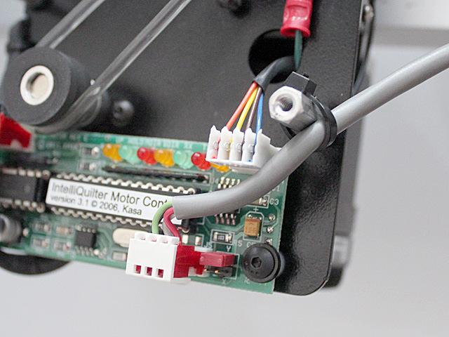 Continue to run the computer cable down at the back of the arm, about 1/2" (13mm) from the rear edge of the machine, using 2-3 adhesive clamps with their opening facing the back.