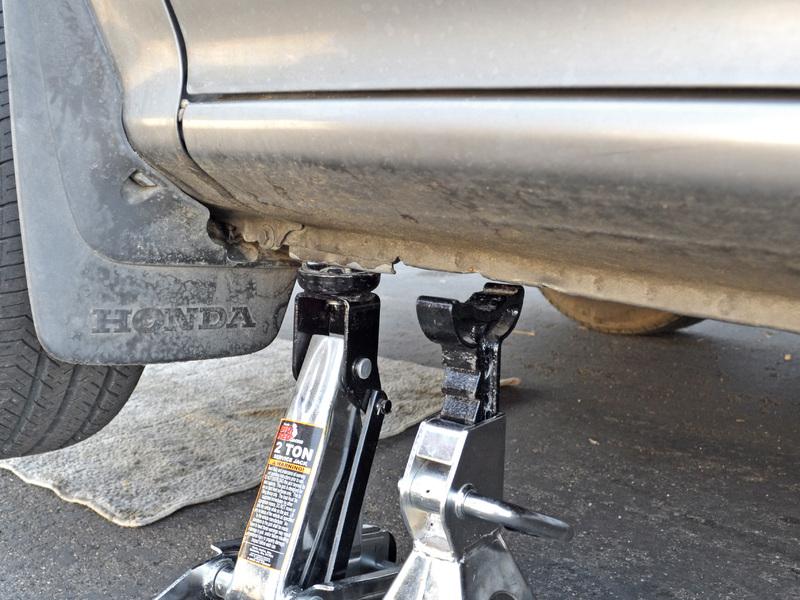 Lift the car with the jack until you can work underneath it. Slide a jack stand under the car, just behind the jack.