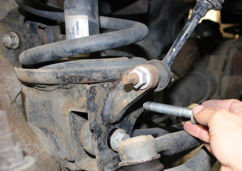 12) Loosen the bolts securing the link arms to the frame and front axle,