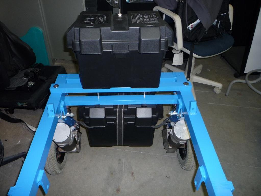 The box that houses the battery is mounted on top of the frame at the back of the chair, and the motor controller box is suspended beneath that box.