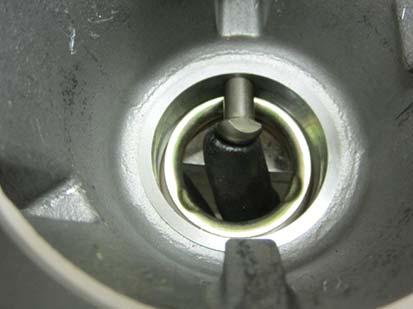 Use a large screwdriver to twist between the spring and housing, forcing the spring from under the lugs