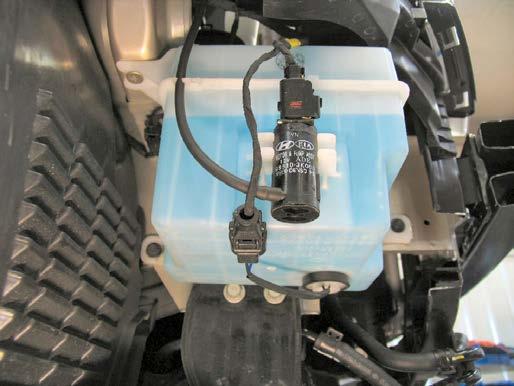 13. Remove two metric bolts from windshield washer reservoir using the 10MM socket. Unplug electrical connections, disconnect and plug water lines.