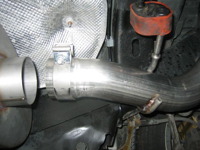 Next, place a clamp over the expanded end of the tailpipe with the nut facing down and insert the hanger nearest the clamp into the rubber grommet (see Fig